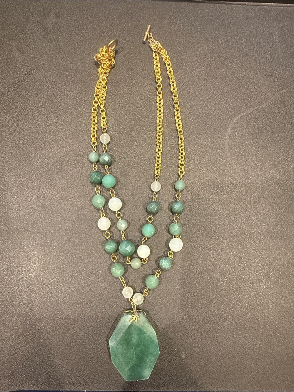 Vintage stone necklace with shades of green featuring a dark green center piece